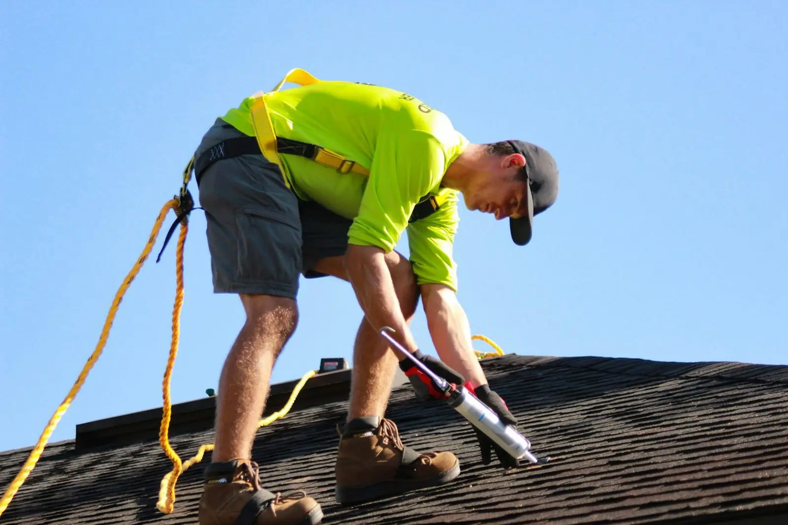 Couvreur encordé fixant une toiture par beau temps